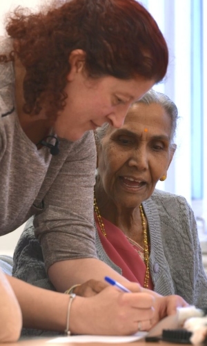 A woman helps an older woman with writing