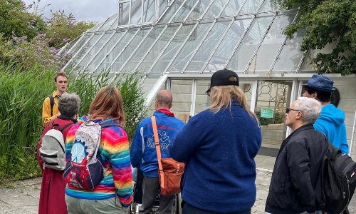 A group of people being led by a tour guide through Kew Gardens