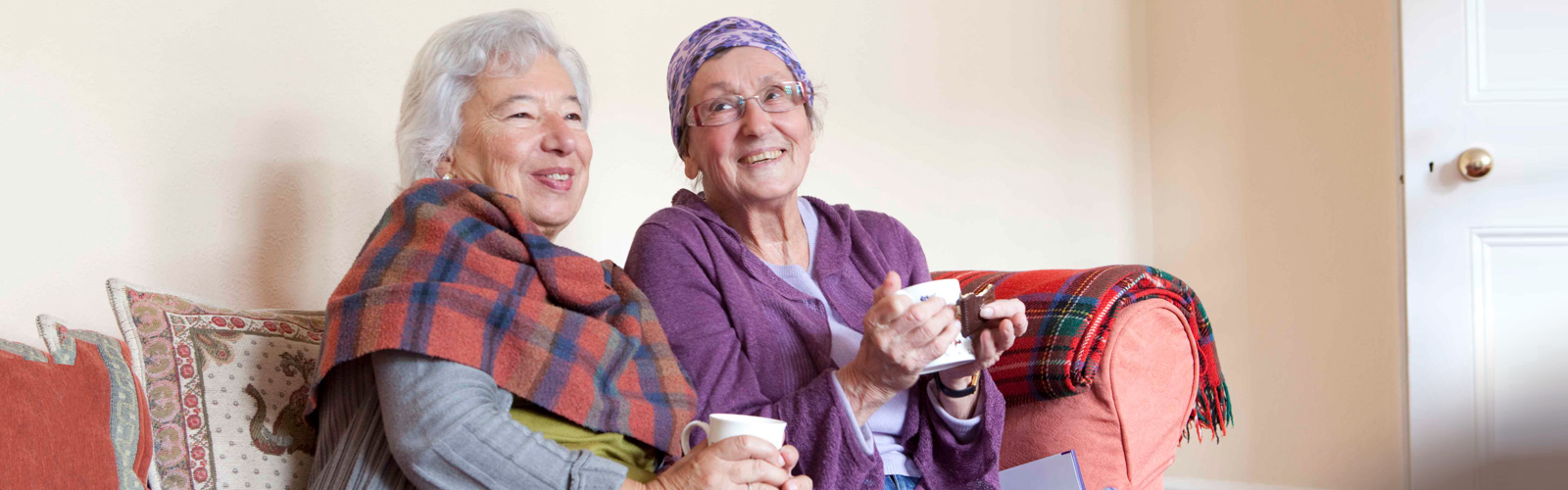 Two older woman cosy up together at home